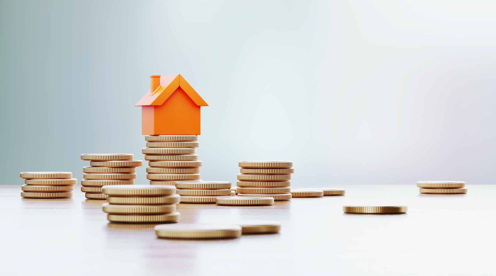 Orange Colored Toy House Sitting over Coin Stacks: Insurance And Real Estate Concept